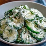 Refreshing cucumber salad tossed in creamy dill dressing, featuring bright herbs and crisp vegetables, ideal as a light vegetarian side dish.