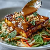 Golden pan-fried tofu cubes top a colorful mix of julienned mango, crisp vegetables, and fresh herbs.  