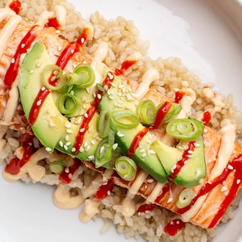This quick Emily Mariko Salmon Rice Bowl features creamy avocado and seaweed alongside flavorful rice.
