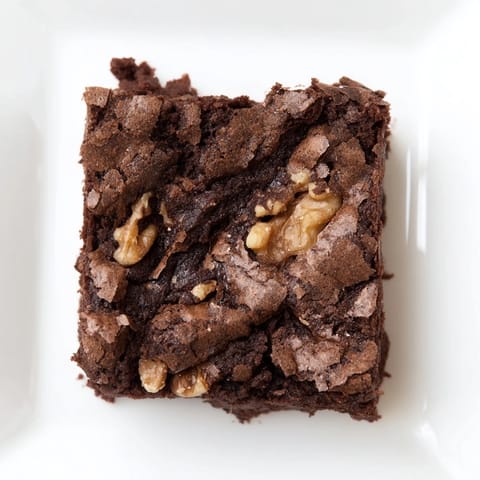 Square, irresistible brownies, rich and dark, fresh from the oven, offering a delightful chocolatey taste.