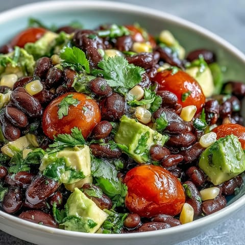 A colorful Black Bean and Veggie Bowl with fresh avocado, cherry tomatoes, and zesty lime dressing, perfect for a quick and healthy meal.  