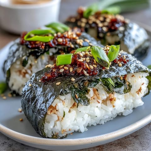 Spicy tuna onigiri with nori wrapping and sesame seeds, perfect for a Japanese-inspired lunch or snack on the go.  