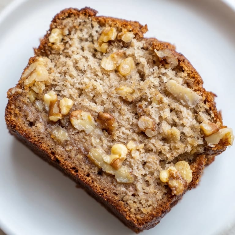Warm, homemade banana bread with visible banana chunks and a dusting of golden crumbs.