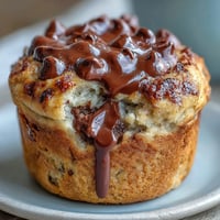 Moist chocolate chip sourdough banana muffins with golden tops and gooey chocolate pockets, perfect for a cozy breakfast or snack.