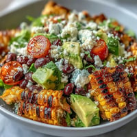 A colorful bowl of grilled corn and black bean taco salad topped with creamy avocado and zesty lime dressing.  